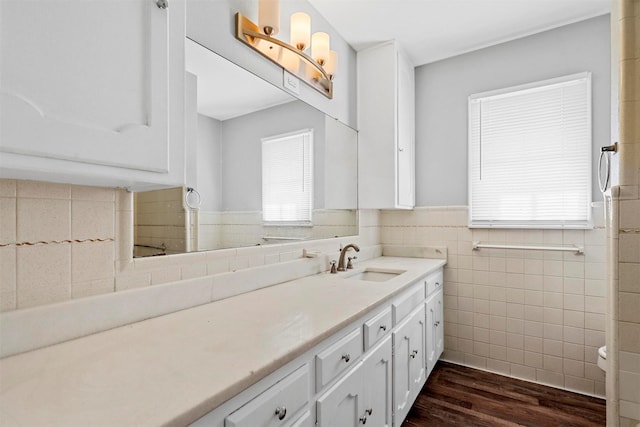 bathroom featuring a wainscoted wall, wood finished floors, vanity, and tile walls