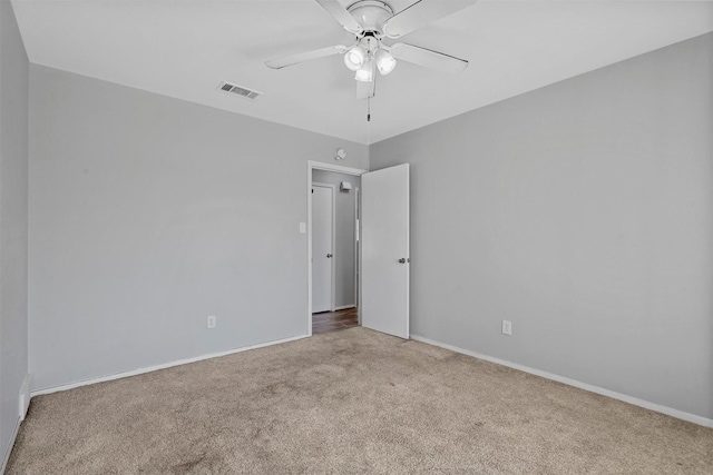 carpeted empty room with ceiling fan, visible vents, and baseboards