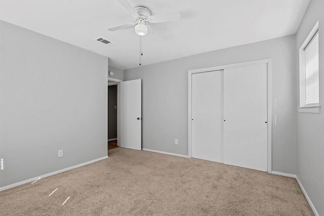 unfurnished bedroom featuring light carpet, baseboards, visible vents, ceiling fan, and a closet