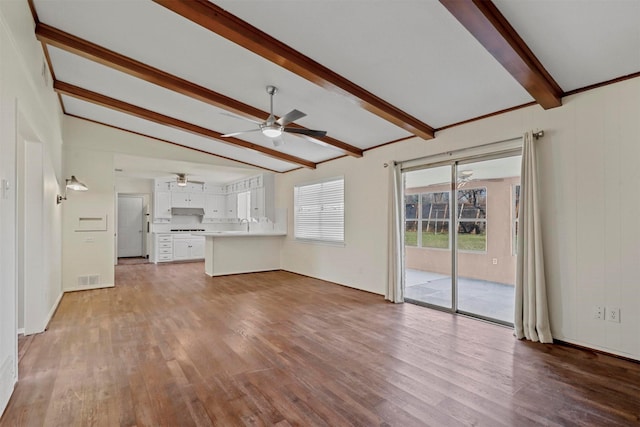 unfurnished living room featuring ceiling fan, visible vents, vaulted ceiling with beams, and wood finished floors