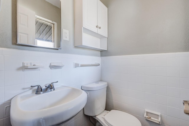 bathroom featuring sink, tile walls, and toilet