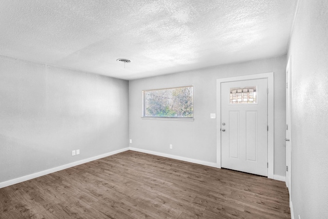 foyer entrance with a textured ceiling and dark wood-type flooring