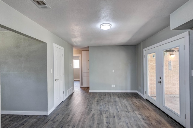 empty room with french doors, dark wood-type flooring, and a textured ceiling