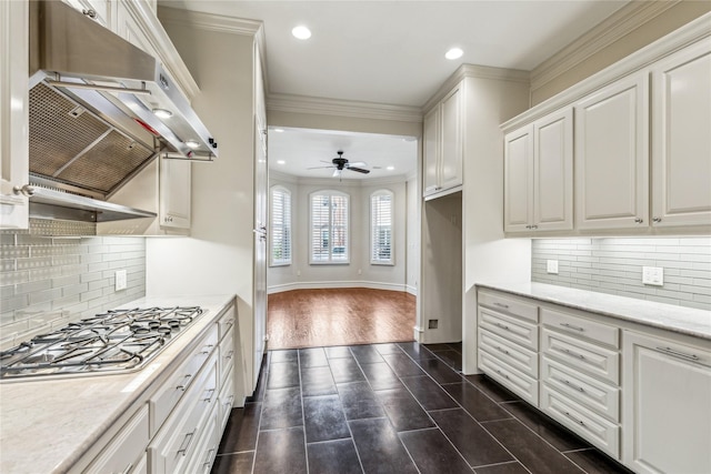 kitchen featuring ceiling fan, white cabinets, stainless steel gas stovetop, ornamental molding, and decorative backsplash