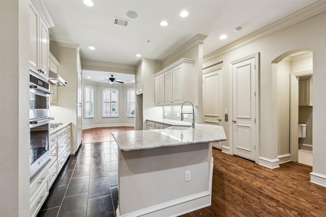 kitchen with dark wood-type flooring, light stone countertops, ceiling fan, sink, and white cabinetry