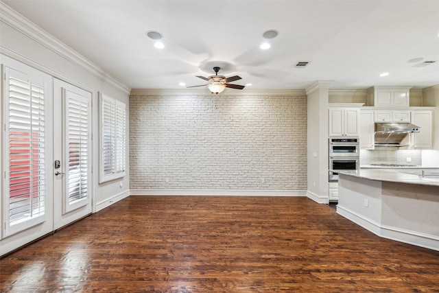 interior space with appliances with stainless steel finishes, brick wall, dark hardwood / wood-style floors, and white cabinets