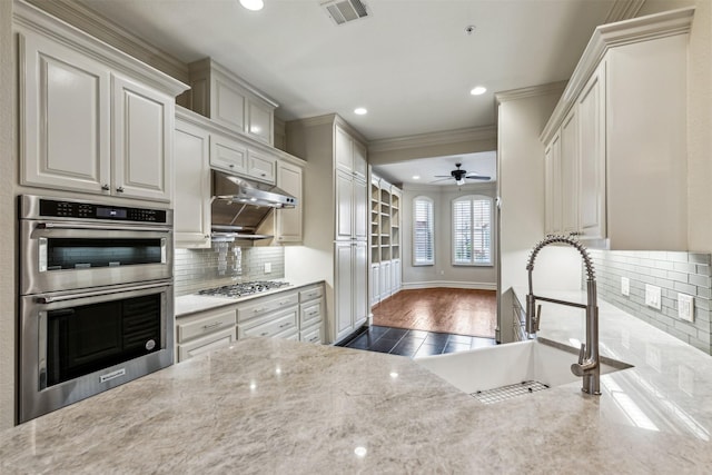 kitchen featuring tasteful backsplash, stainless steel appliances, white cabinets, ornamental molding, and sink