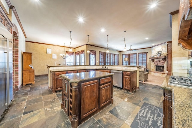 kitchen with hanging light fixtures, a center island, appliances with stainless steel finishes, and a large fireplace