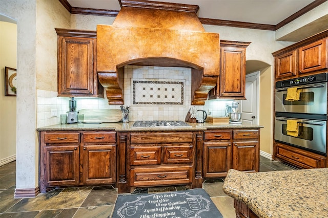 kitchen featuring custom exhaust hood, light stone counters, appliances with stainless steel finishes, crown molding, and decorative backsplash