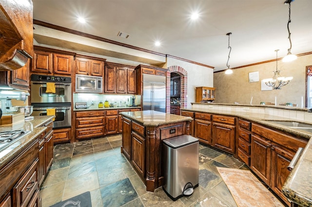 kitchen featuring built in appliances, tasteful backsplash, hanging light fixtures, a center island, and sink