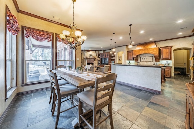 dining room with a large fireplace, crown molding, and an inviting chandelier