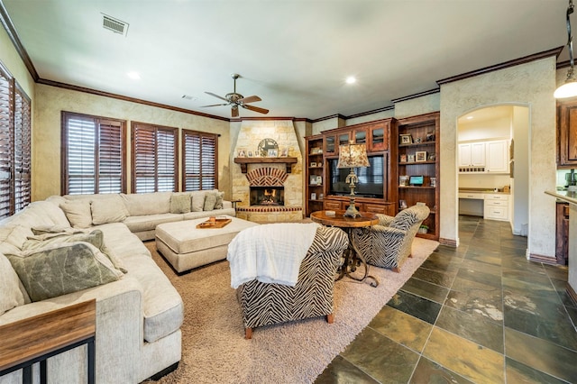 living room featuring a fireplace, ceiling fan, and crown molding