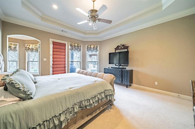 bedroom featuring a tray ceiling, carpet floors, multiple windows, and ornamental molding