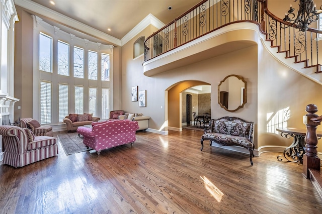 living room featuring a high ceiling, hardwood / wood-style flooring, and crown molding