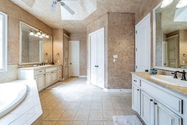 bathroom featuring tile patterned floors, tiled bath, vanity, and ceiling fan