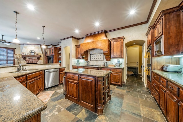 kitchen with appliances with stainless steel finishes, hanging light fixtures, premium range hood, a kitchen island, and sink