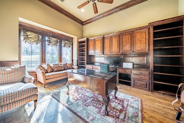 office area with ceiling fan, crown molding, a towering ceiling, and light hardwood / wood-style flooring