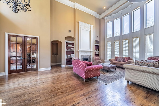 living room with hardwood / wood-style floors, french doors, ornamental molding, and a fireplace