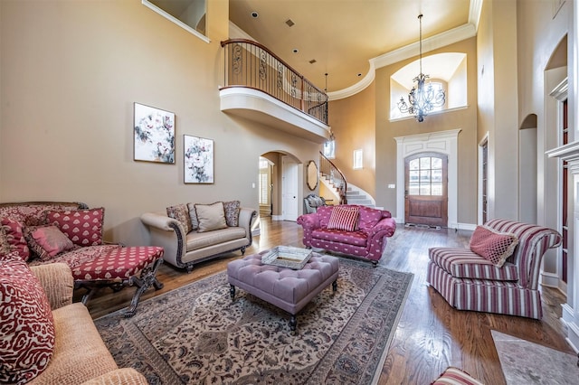 living room featuring hardwood / wood-style flooring, ornamental molding, a chandelier, and a high ceiling