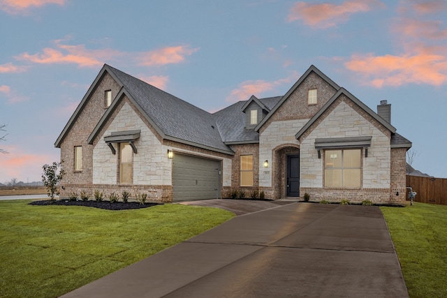 french country home with a yard and a garage