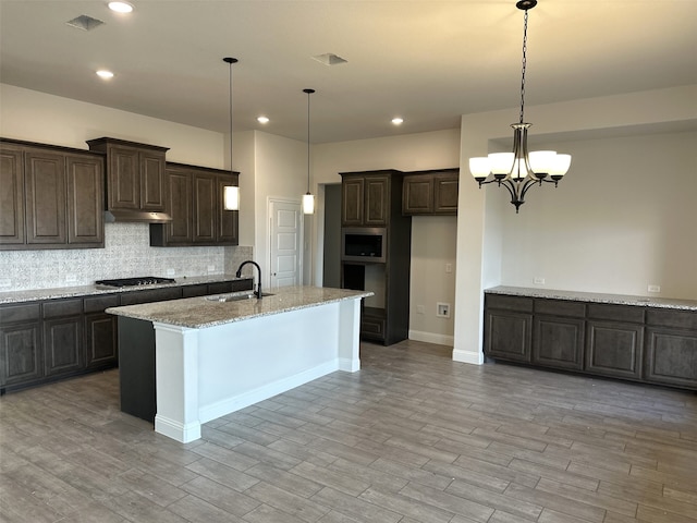 kitchen with appliances with stainless steel finishes, decorative light fixtures, sink, and light stone countertops