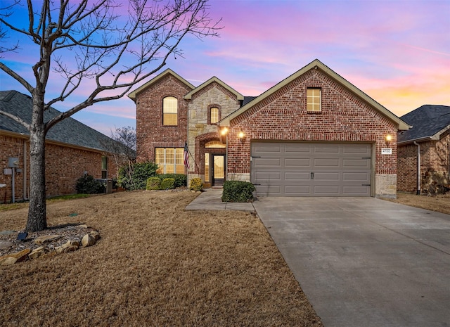 traditional home with a garage, stone siding, brick siding, and driveway