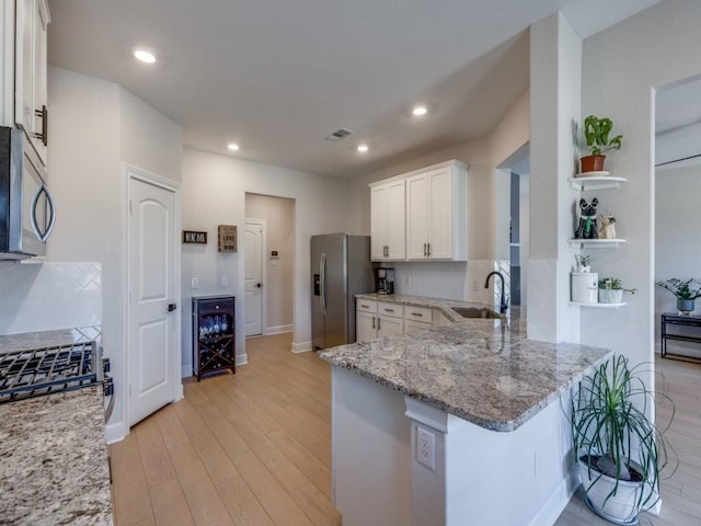 kitchen with light wood-type flooring, white cabinetry, appliances with stainless steel finishes, and visible vents