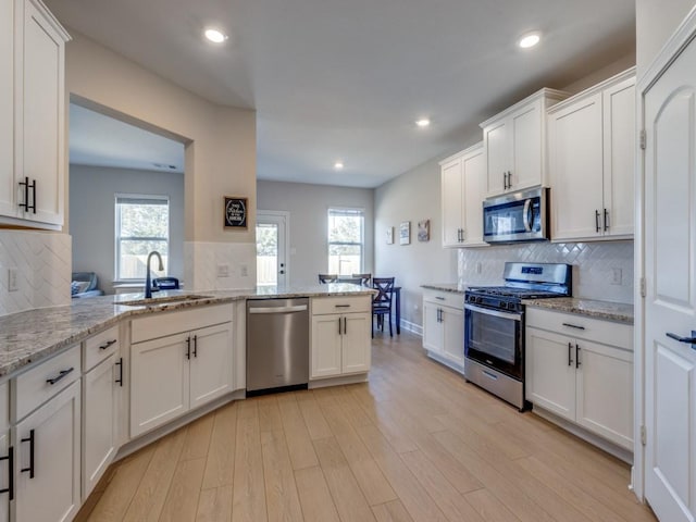 kitchen featuring a sink, white cabinetry, recessed lighting, stainless steel appliances, and light wood-style floors