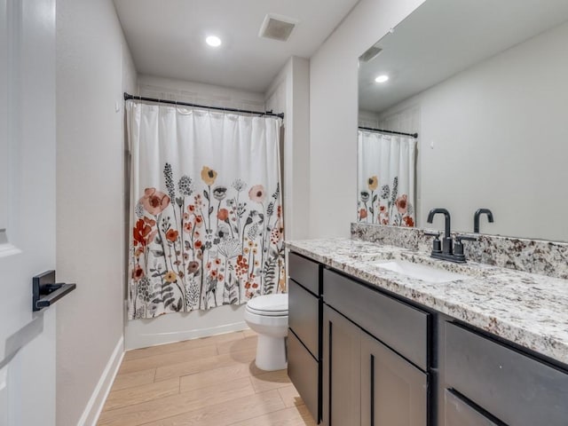 bathroom featuring visible vents, shower / bath combo with shower curtain, toilet, wood finished floors, and vanity