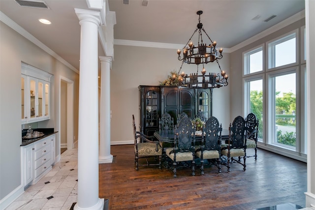 dining space with ornate columns, crown molding, a notable chandelier, and light hardwood / wood-style flooring