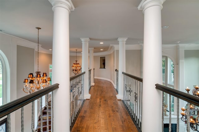 hall featuring ornamental molding, dark wood-type flooring, a chandelier, and decorative columns