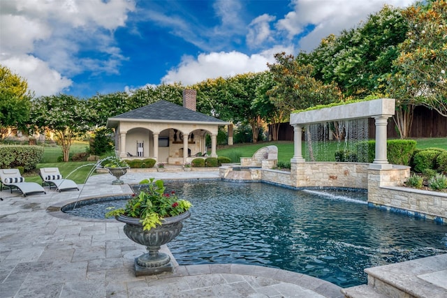 view of swimming pool with pool water feature, a patio area, an outdoor structure, and a lawn