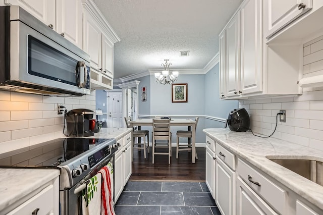 kitchen with visible vents, appliances with stainless steel finishes, ornamental molding, and white cabinetry