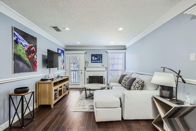 living room featuring dark wood-style floors, a tiled fireplace, visible vents, and crown molding