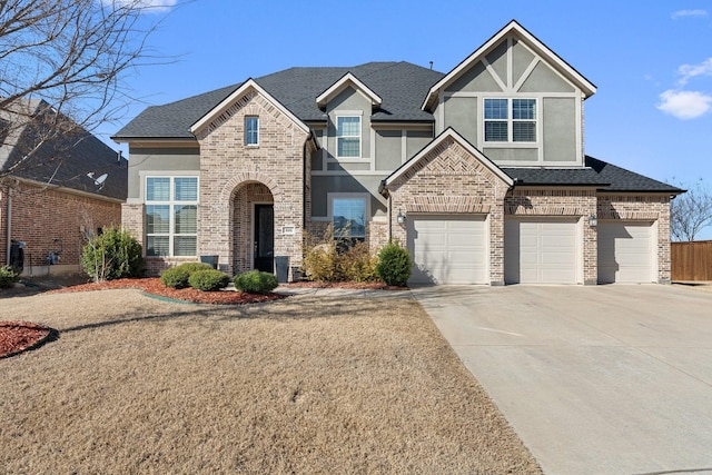 view of front of house with roof with shingles, brick siding, driveway, and stucco siding