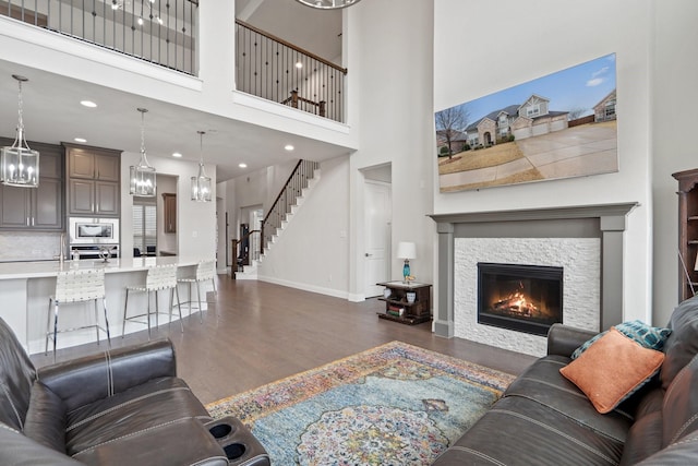 living area featuring recessed lighting, a fireplace, baseboards, stairway, and dark wood-style floors