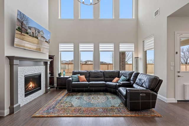 living room featuring a healthy amount of sunlight, visible vents, hardwood / wood-style floors, and a glass covered fireplace