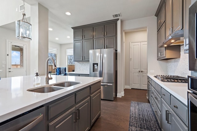 kitchen featuring under cabinet range hood, a sink, visible vents, light countertops, and appliances with stainless steel finishes