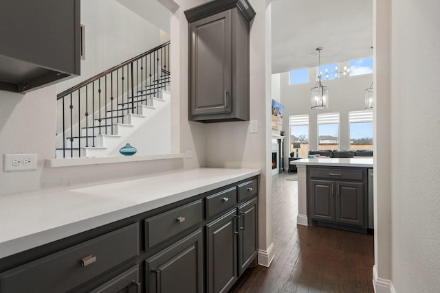 bar featuring baseboards, a towering ceiling, dark wood-type flooring, stairs, and a fireplace