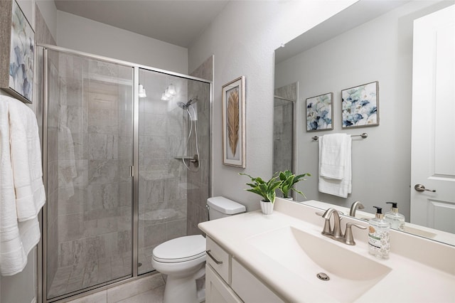 bathroom with a stall shower, vanity, toilet, and tile patterned floors