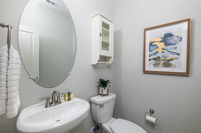 half bath featuring toilet, a sink, and visible vents