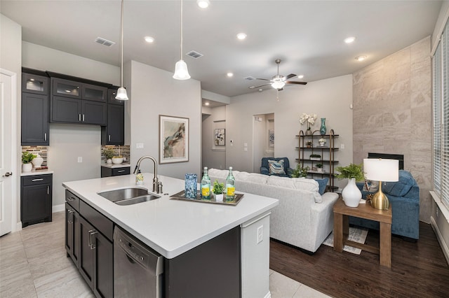 kitchen with light countertops, visible vents, stainless steel dishwasher, open floor plan, and a sink