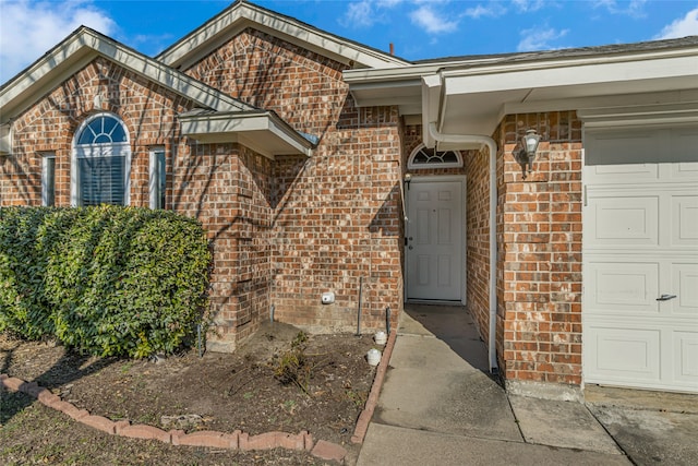 doorway to property with brick siding and a garage