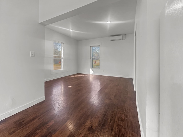 unfurnished room with dark wood-type flooring, a wall mounted air conditioner, and baseboards