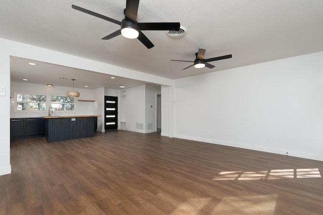 unfurnished living room featuring dark hardwood / wood-style flooring, ceiling fan, and a textured ceiling