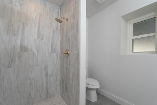 bathroom featuring tile patterned floors, tiled shower, and toilet