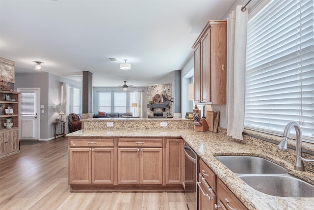2745 Sunlight Dr, Little Elm, TX 75068 - kitchen featuring light wood-type flooring, kitchen peninsula, sink, stainless steel dishwasher, and light stone counters