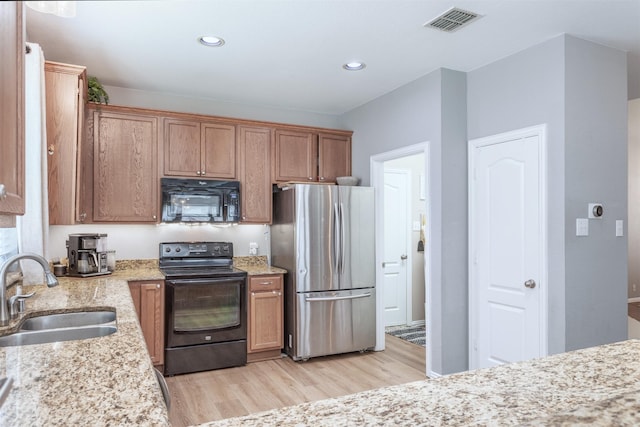 2745 Sunlight Dr, Little Elm, TX 75068 - kitchen with sink, black appliances, light stone countertops, and light hardwood / wood-style flooring
