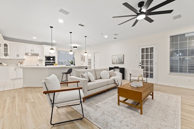 living room featuring ceiling fan, light hardwood / wood-style flooring, and crown molding