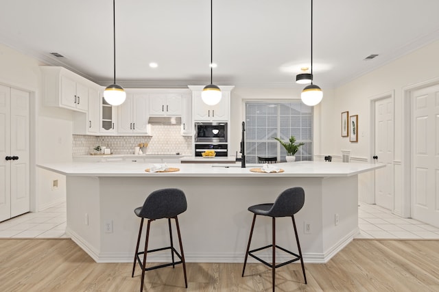 kitchen featuring a large island, a kitchen breakfast bar, white cabinets, black appliances, and decorative light fixtures